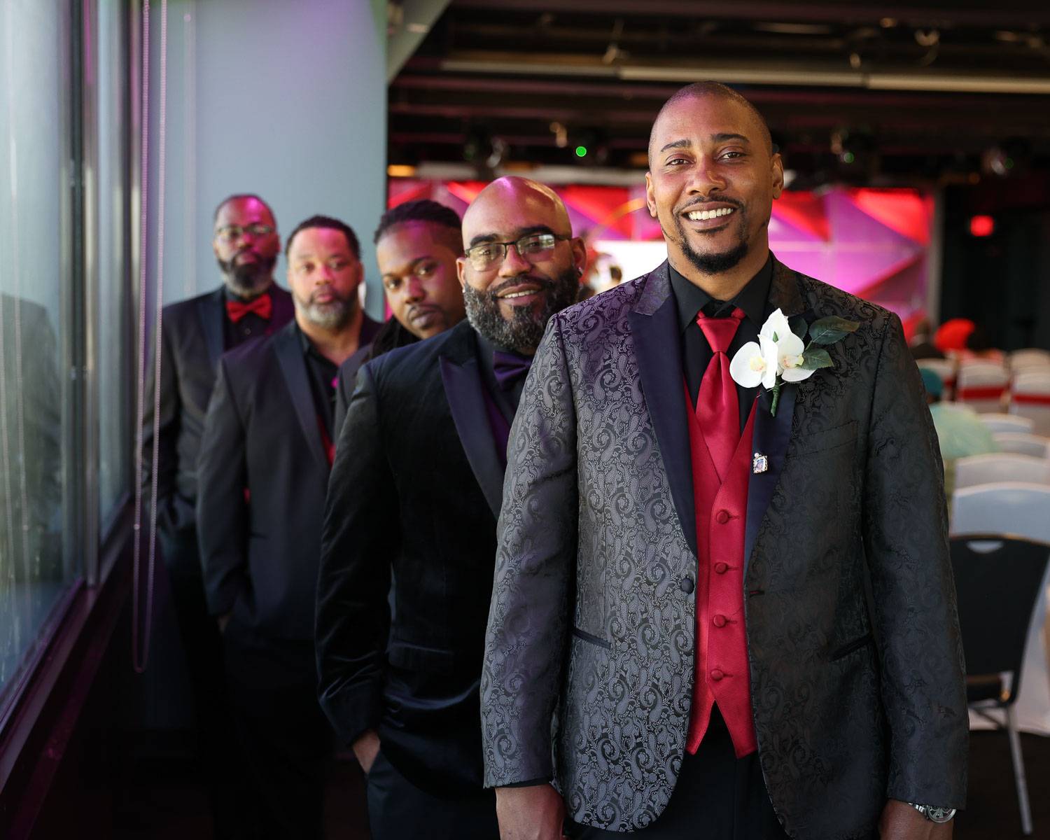 The groom smiles with his groomsmen behind him