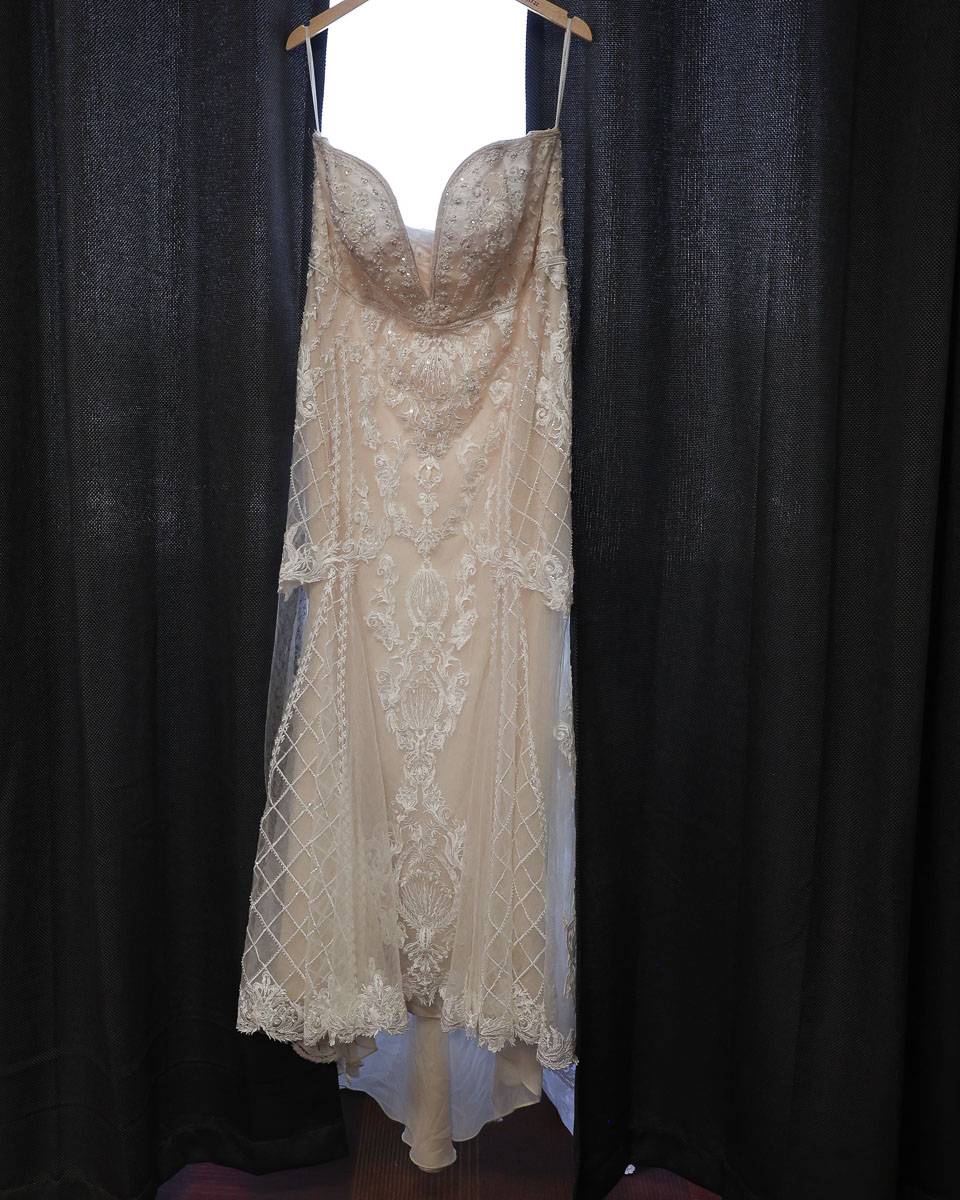The bride’s dress hanging near the curtains