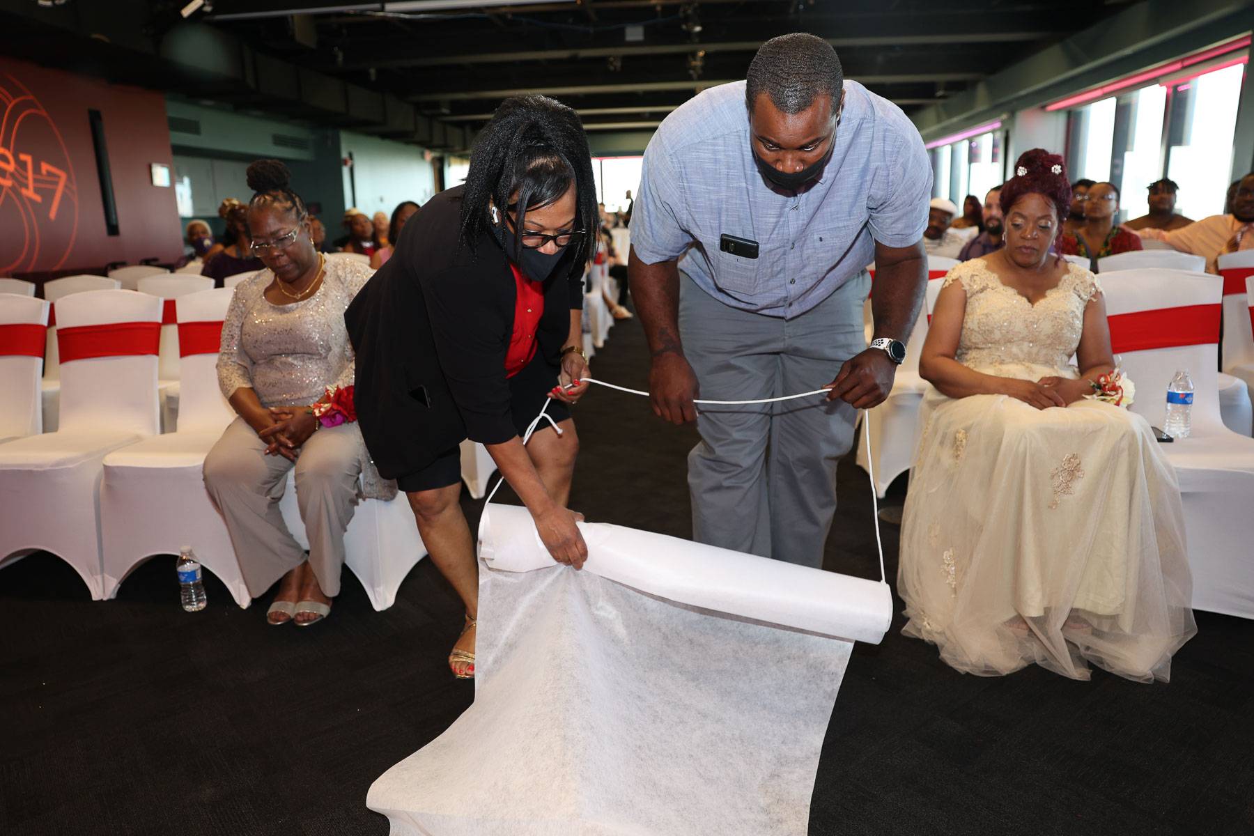 Two people rolling out the white carpet
