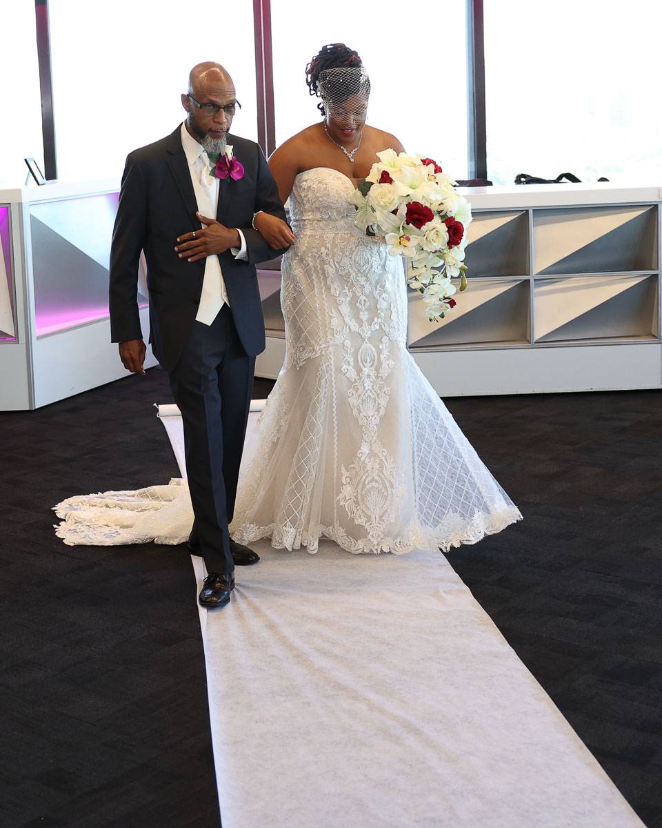 The bride and her father walking on the white carpet