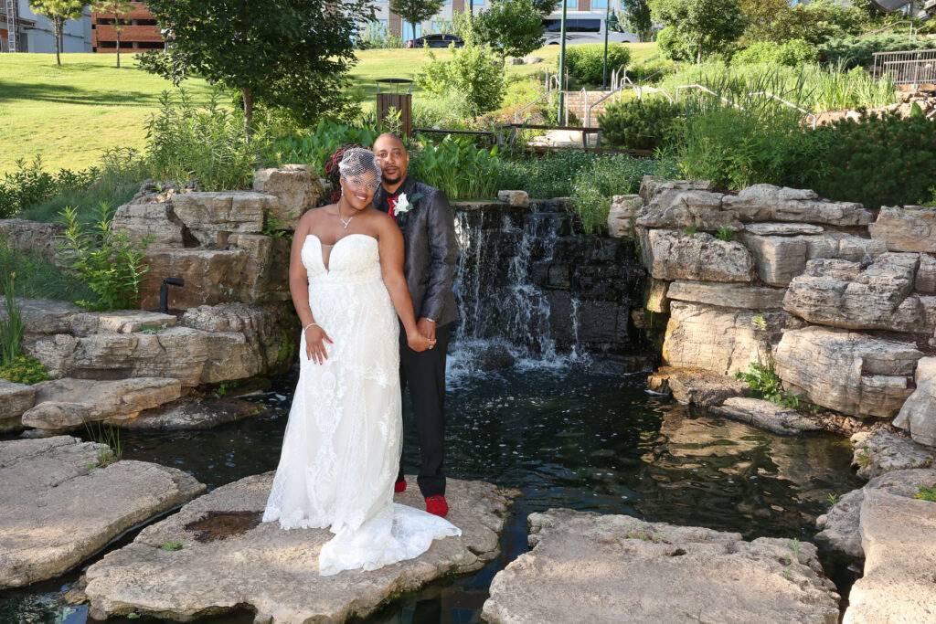 The bride and groom standing by a waterfall and pond