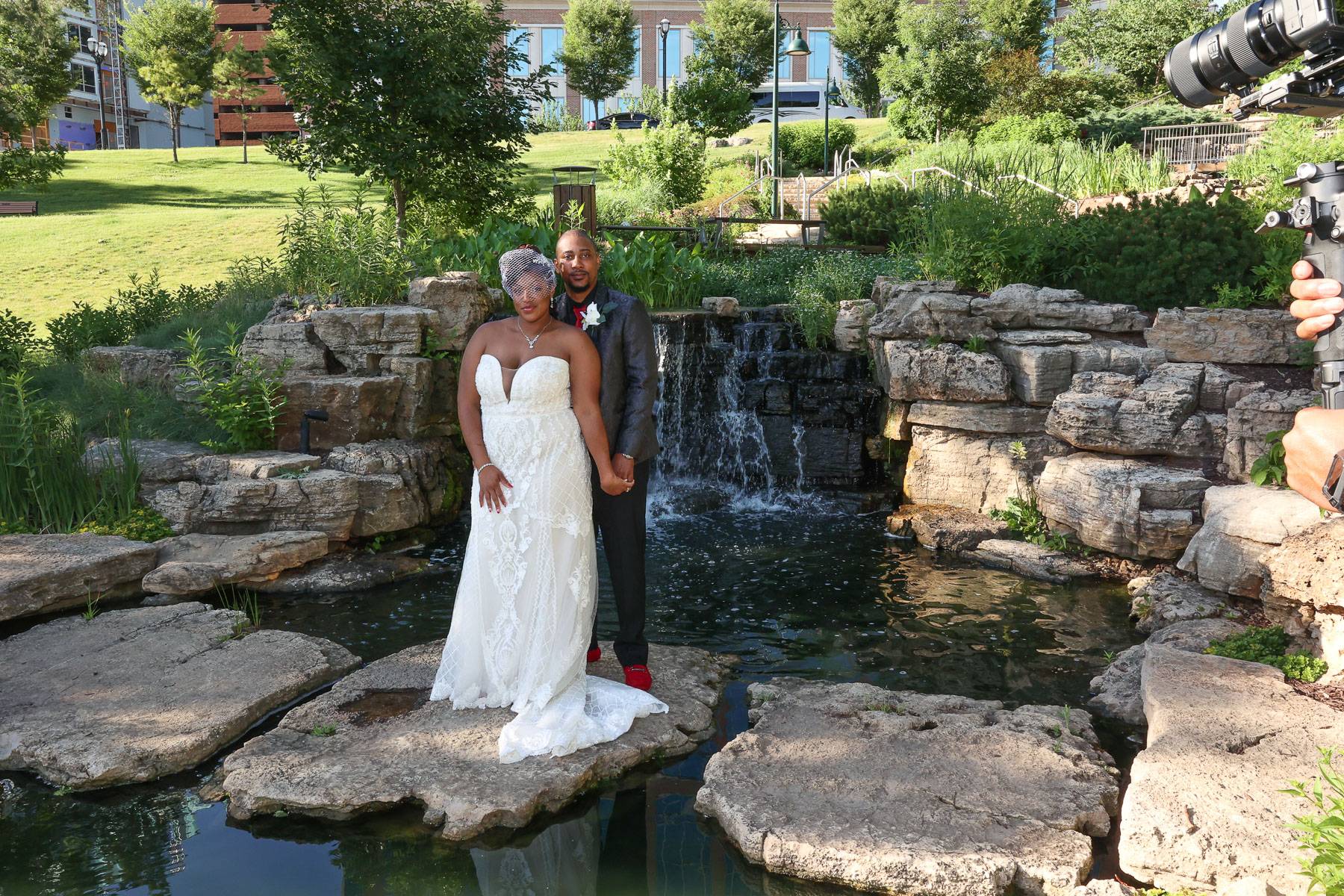 The newlyweds standing by a pond and waterfall