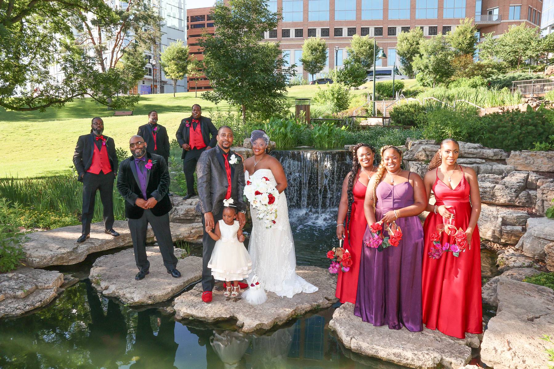 The newlyweds and their attendants grouped around the pond