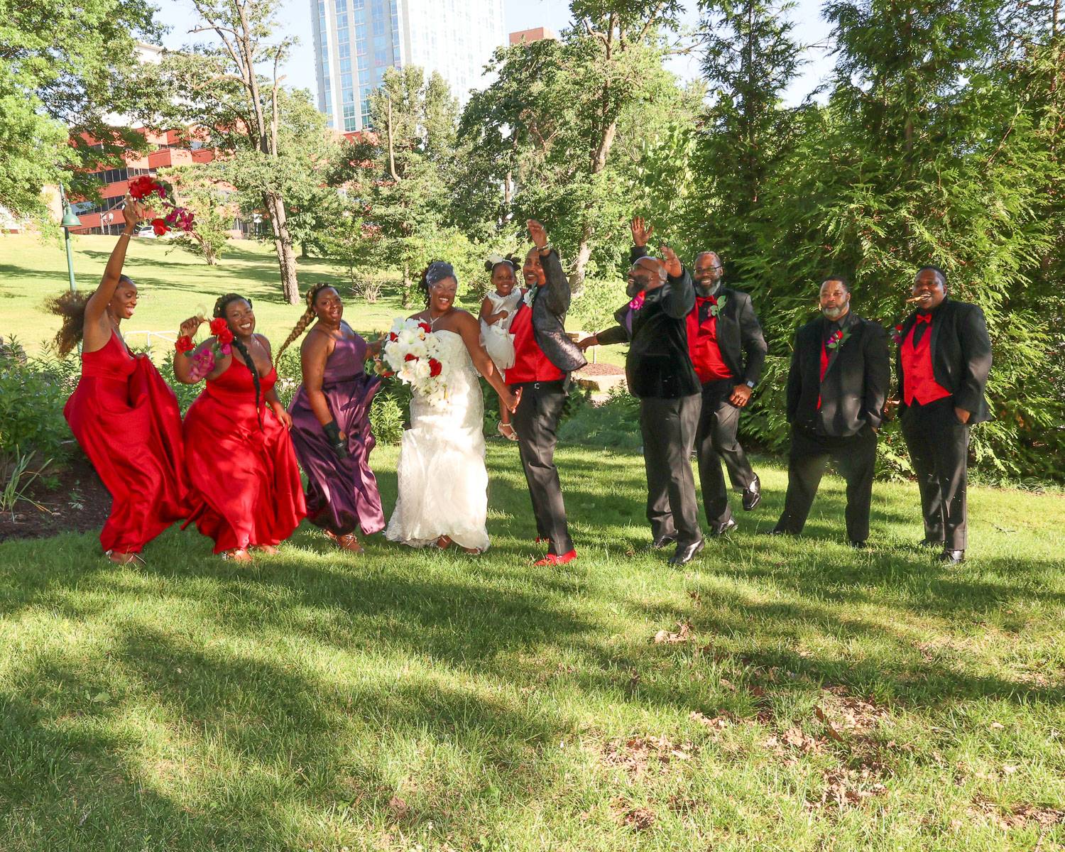 The newlyweds and their attendants jumping on grass