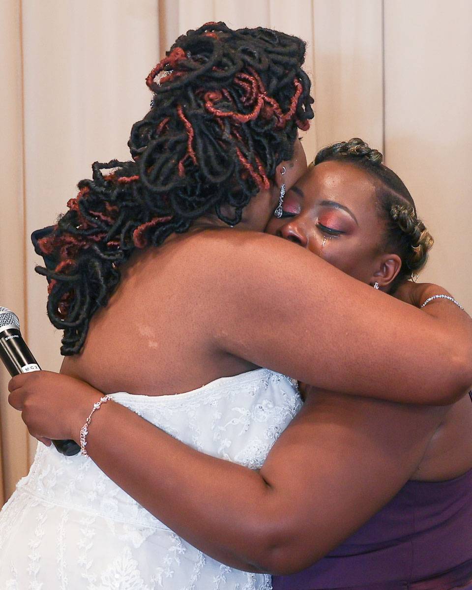 The bride and her friend hug with tears on their faces