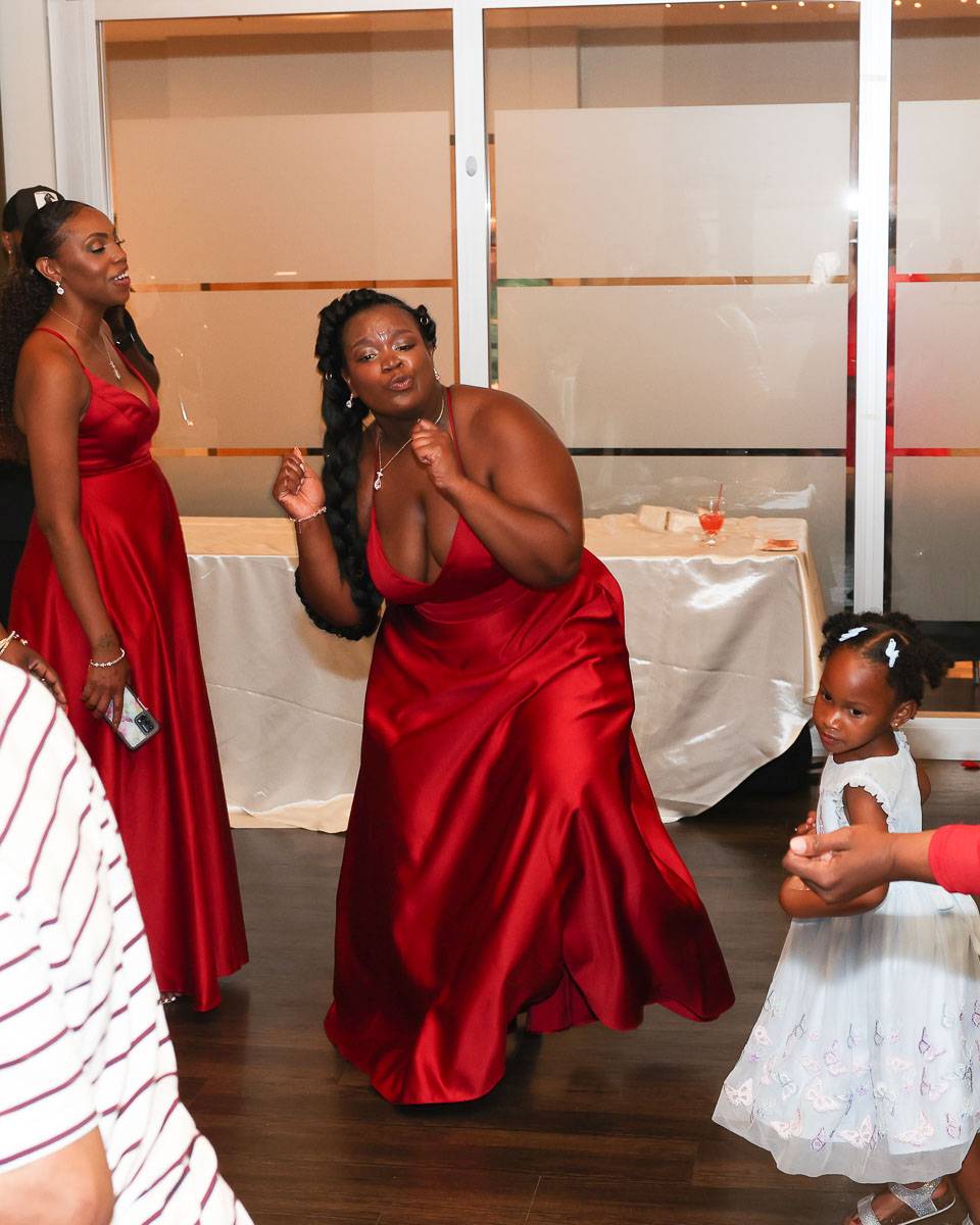 One of the bridesmaids in red dancing
