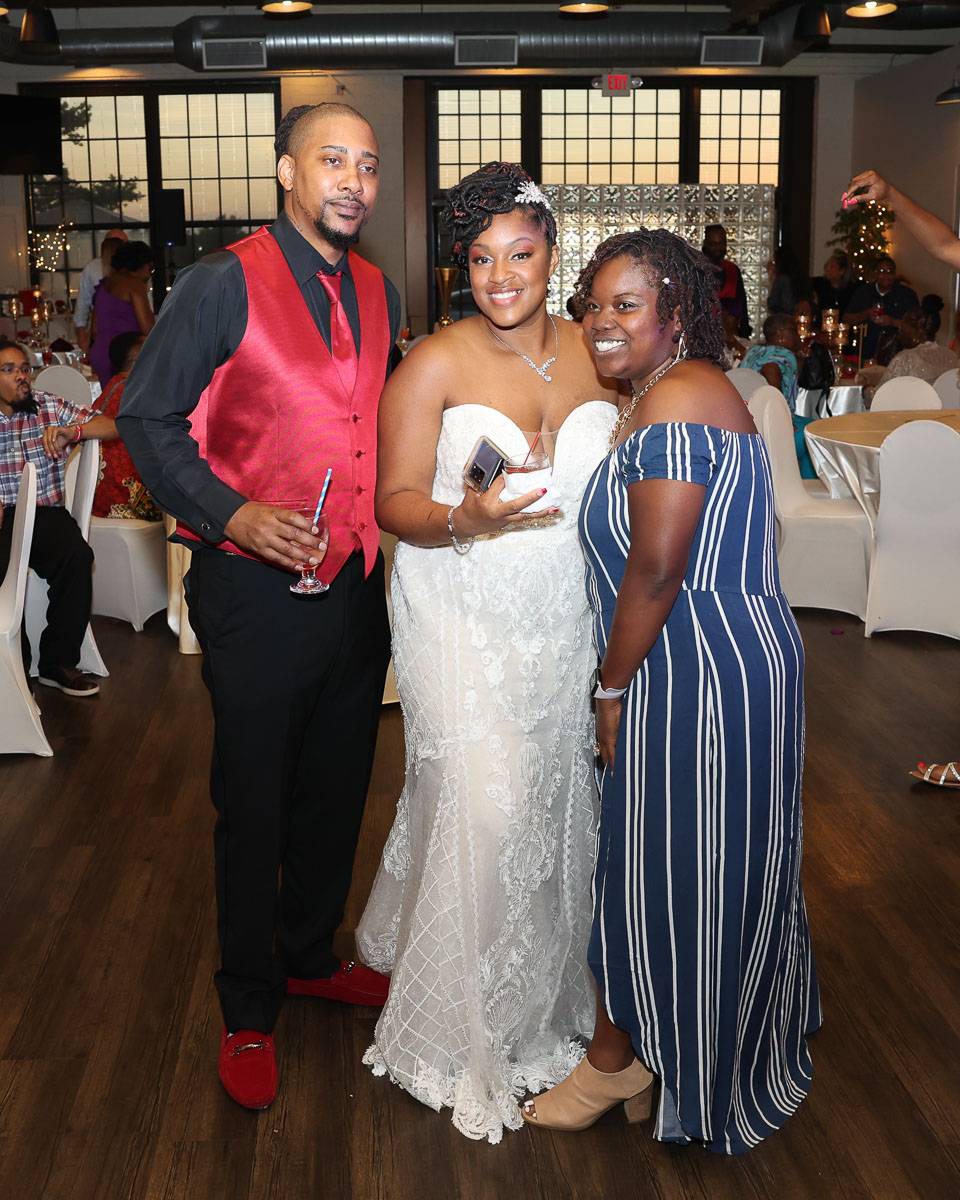 The newlyweds with a woman who has a striped dress