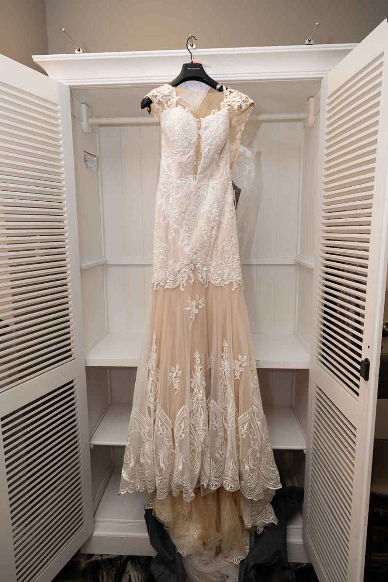 The white wedding dress hanging from the dresser