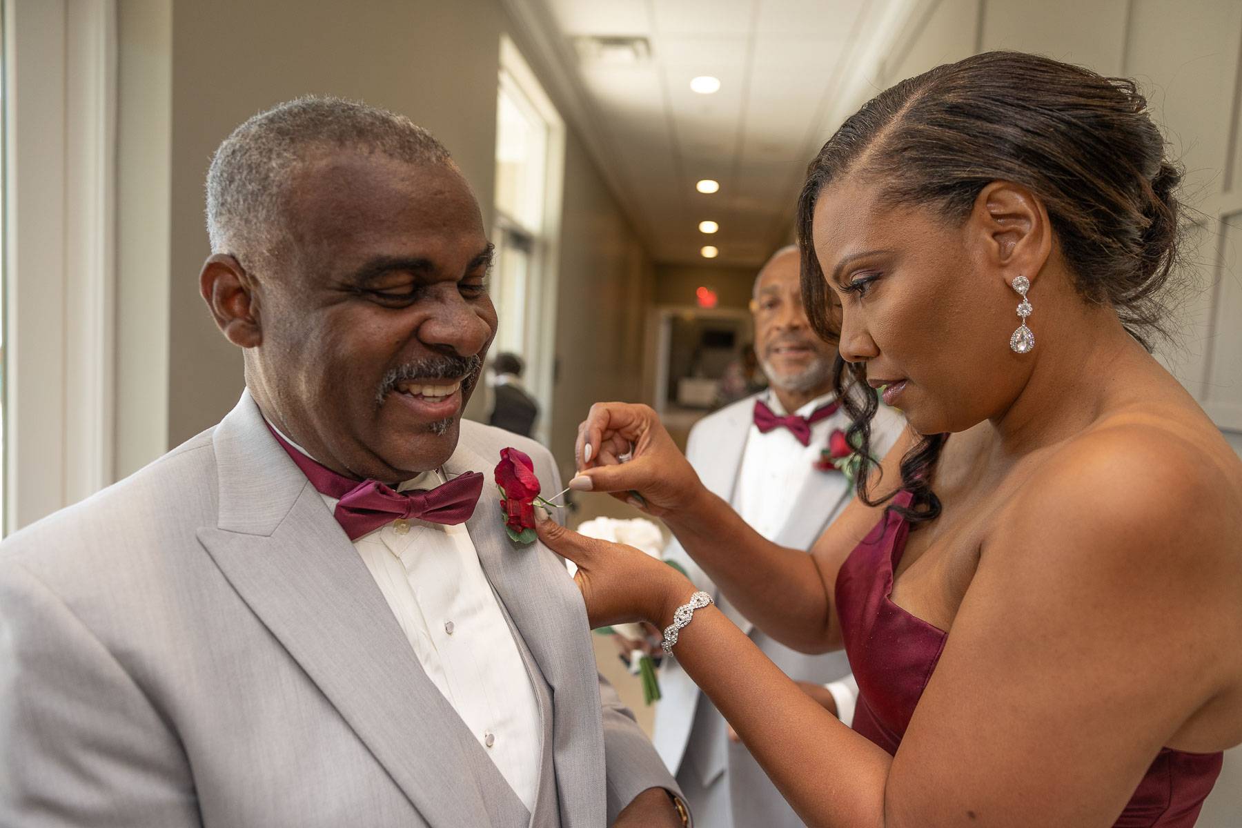 A woman fixing a man’s boutonniere